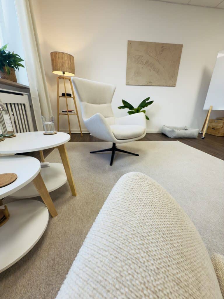 Heller und modern eingerichteter Behandlungsraum für Psychotherapie in Rosenheim mit bequemem Sessel und Pflanzen.