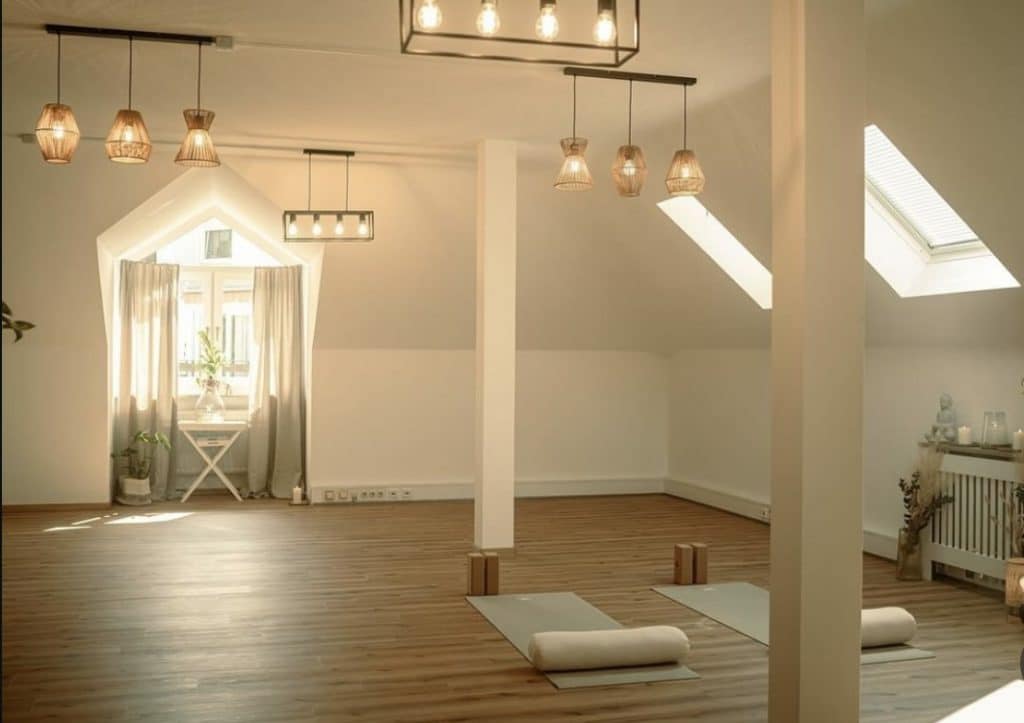 Ein heller, ruhiger Dachboden-Yogaraum, ausgestattet mit Matten und Hilfsmitteln, der als Ort für die im Blogbeitrag beschriebene Psychotherapie und Yogatherapie in Rosenheim dient.